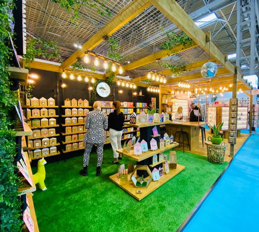 Tache’s trade-show stand seen from the aisle, with shelved card ranges and a central display table