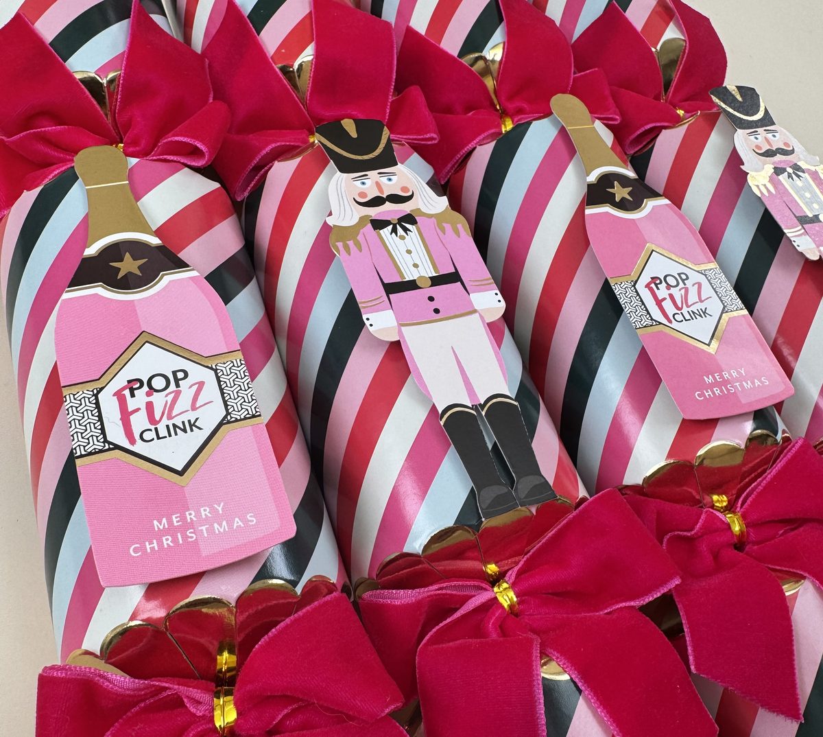 Striped Christmas crackers with velvet bows and die-cut champagne-bottle and nutcracker toppers