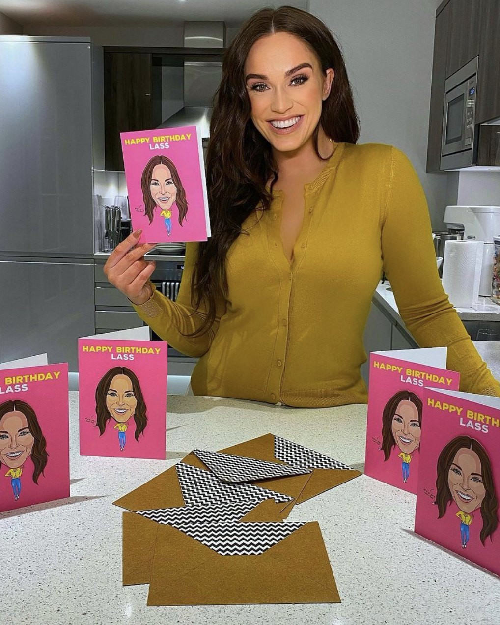 Vicky Pattison holding the birthday card Tache created with her, with more copies and envelopes on the worktop